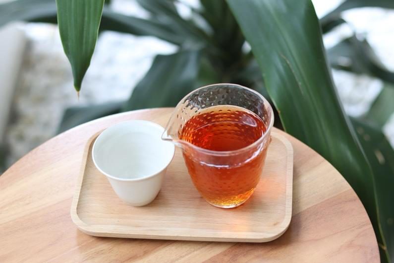 Japanese brewed tea served in a glass pot on a wooden tray